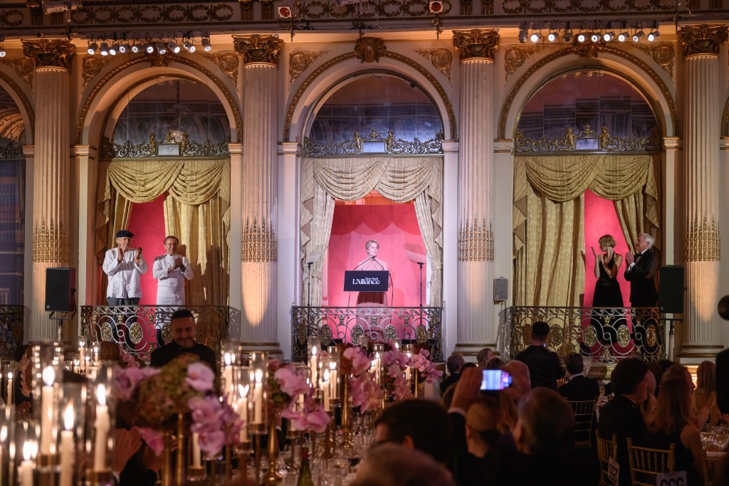 A grand ballroom setting at the 2025 L'Alliance New York Gala, featuring elegantly dressed guests, ornate decor, and a speaker at a podium with applause from the audience.