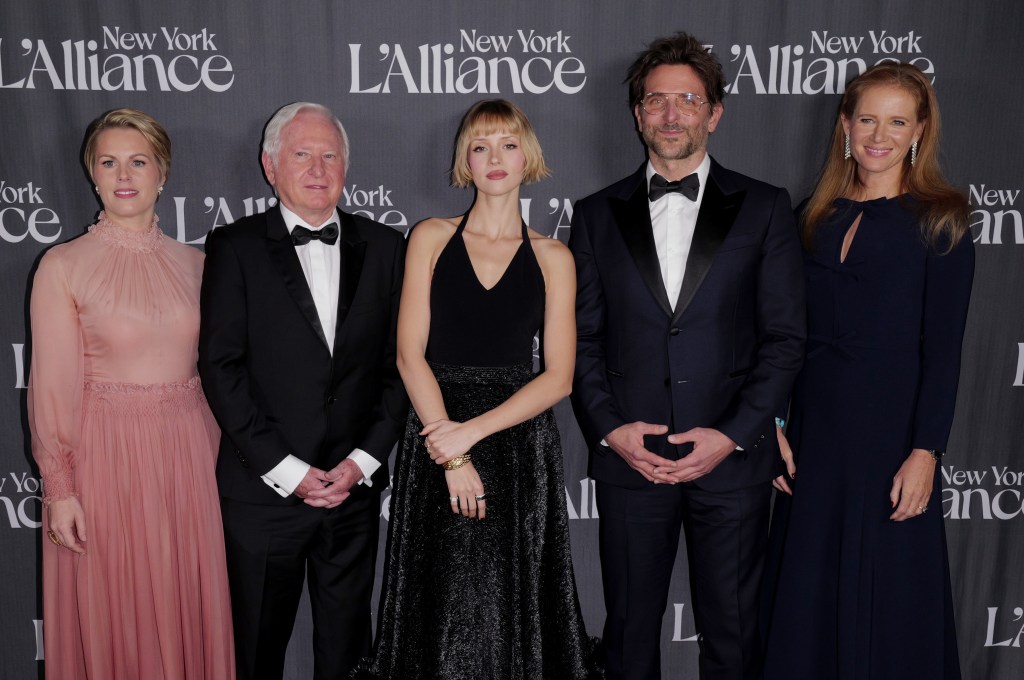 A group of five elegantly dressed individuals poses together in front of a backdrop for the New York L'Alliance event, showcasing their formal attire and the glamorous atmosphere of the gala.